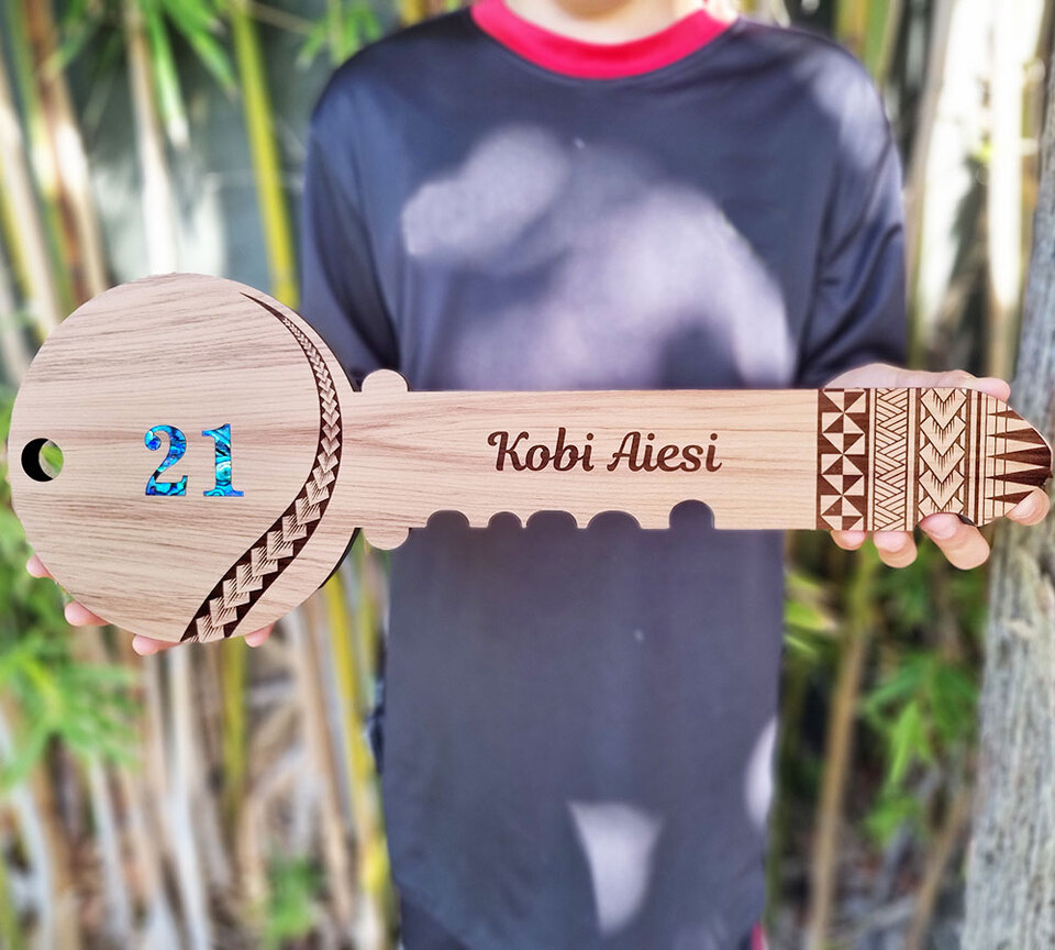 Engraved 21st key with pasifika designs held by a person